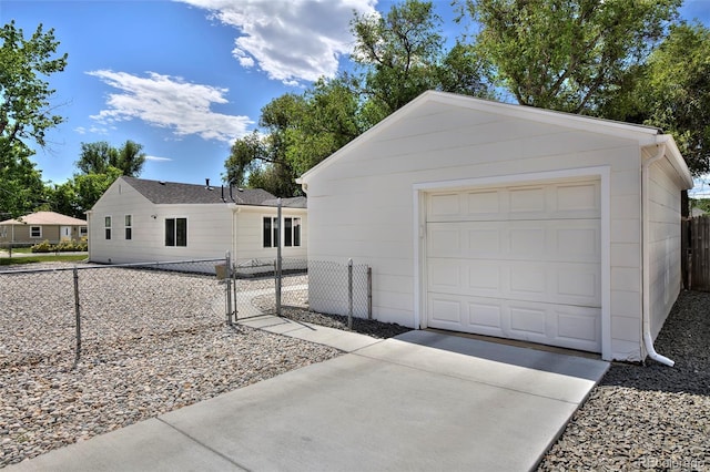 detached garage featuring driveway, a gate, and fence