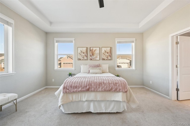 bedroom with a tray ceiling, light colored carpet, and ceiling fan