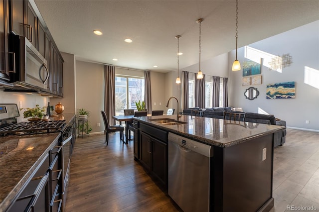 kitchen featuring pendant lighting, sink, appliances with stainless steel finishes, a kitchen island with sink, and dark brown cabinetry