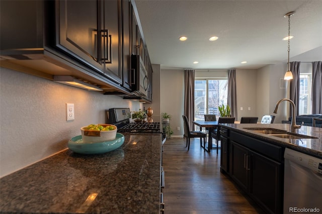 kitchen featuring appliances with stainless steel finishes, pendant lighting, sink, dark stone counters, and dark wood-type flooring