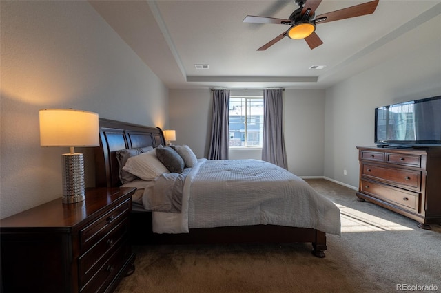 carpeted bedroom featuring ceiling fan and a tray ceiling