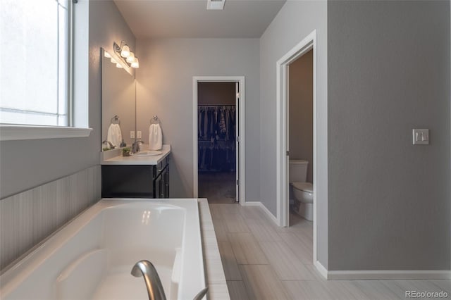 bathroom featuring vanity, a bath, and toilet