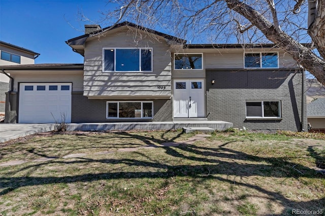 view of front of home featuring a front lawn, brick siding, a garage, and driveway