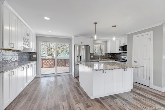 kitchen featuring light wood finished floors, ornamental molding, a sink, appliances with stainless steel finishes, and white cabinetry