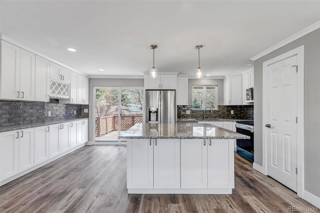 kitchen with crown molding, stainless steel appliances, wood finished floors, white cabinetry, and a sink