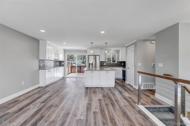 kitchen with white cabinets, visible vents, stainless steel refrigerator with ice dispenser, and a kitchen island