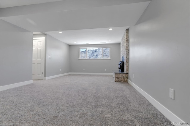 basement featuring carpet flooring, recessed lighting, a wood stove, and baseboards