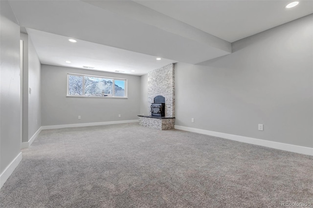 unfurnished living room featuring visible vents, baseboards, carpet, recessed lighting, and a wood stove