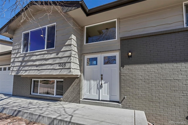 entrance to property with a garage and brick siding