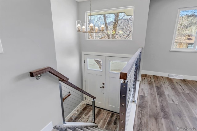 entryway with a chandelier, baseboards, visible vents, and wood finished floors