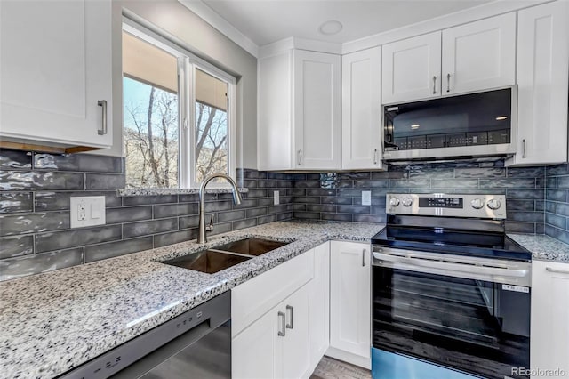 kitchen with a sink, stainless steel appliances, light stone countertops, and white cabinetry