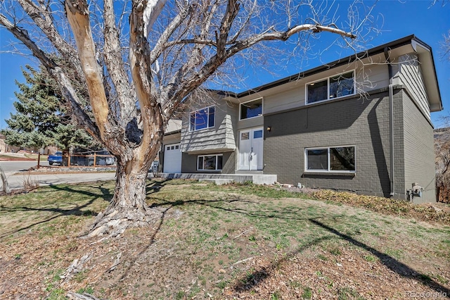 view of front of home with brick siding, a front lawn, and a garage