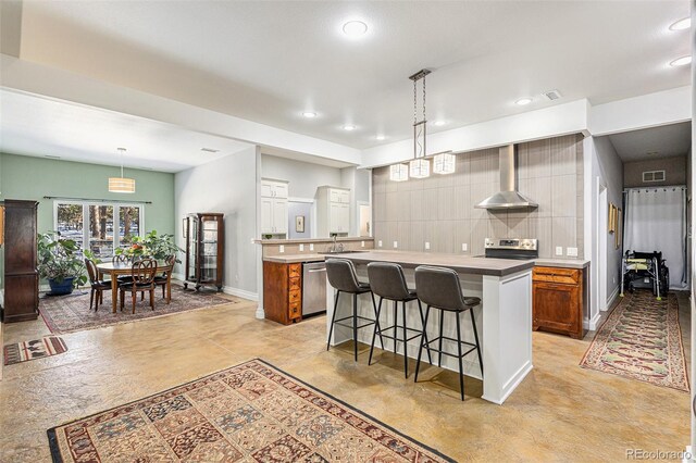 kitchen with wall chimney range hood, a kitchen island, and brown cabinetry