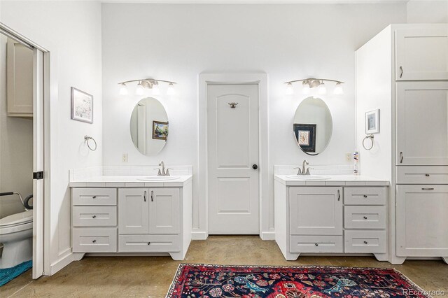 full bathroom with two vanities, a sink, and toilet