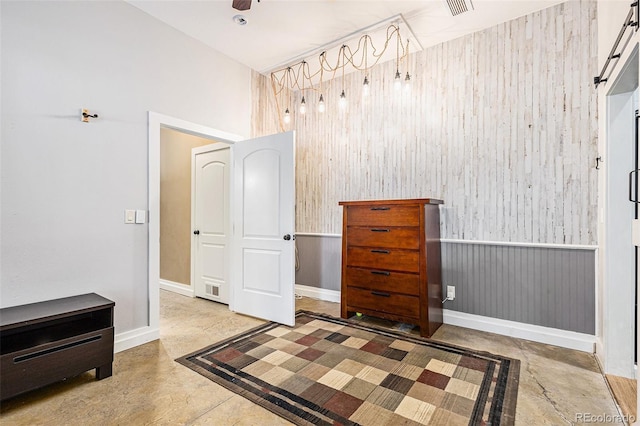 bedroom featuring a wainscoted wall, concrete floors, and visible vents