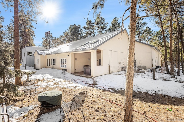 snow covered house with metal roof and stucco siding