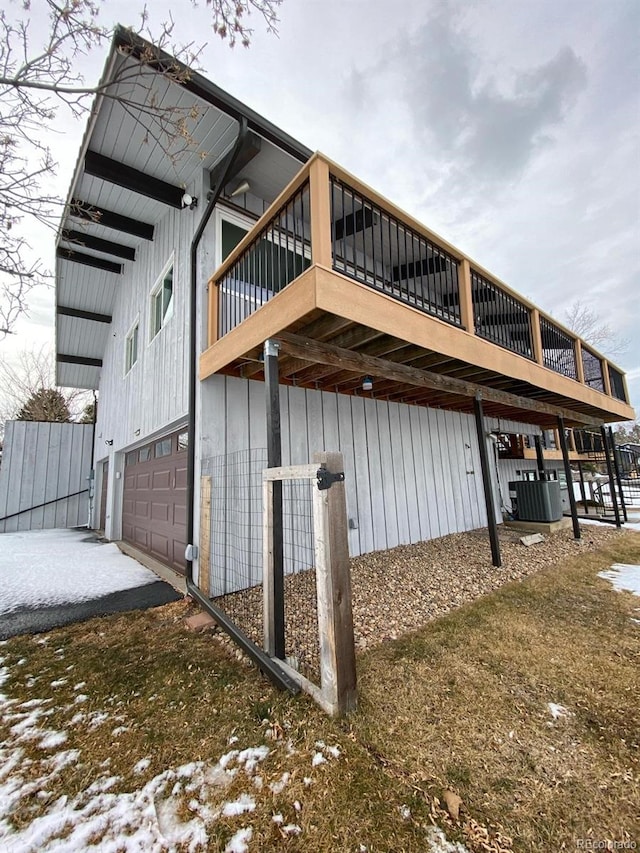 view of snowy exterior with a garage and central AC