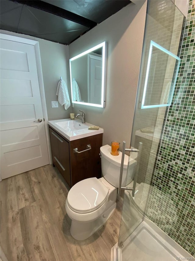 bathroom featuring a shower with door, vanity, hardwood / wood-style floors, and toilet