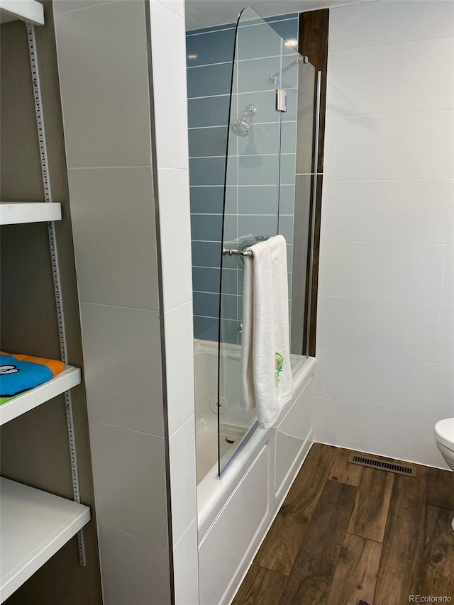 bathroom with tiled shower / bath, wood-type flooring, and toilet