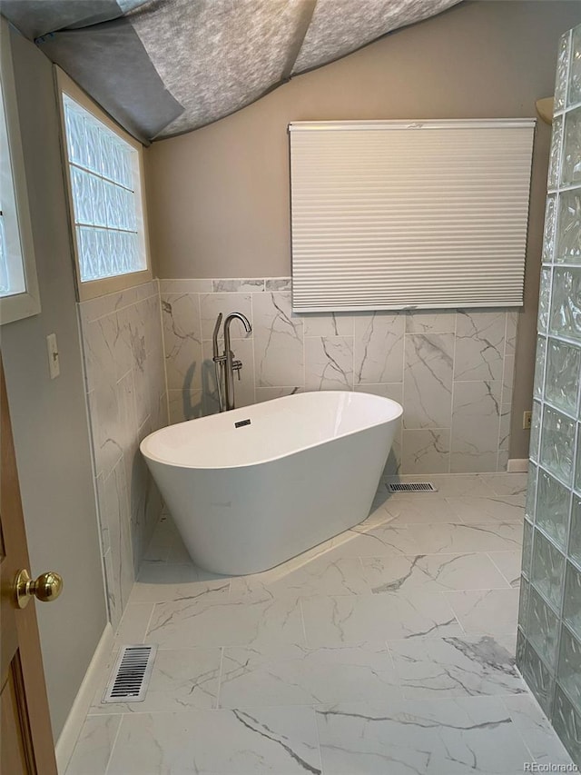 bathroom with vaulted ceiling and a bath