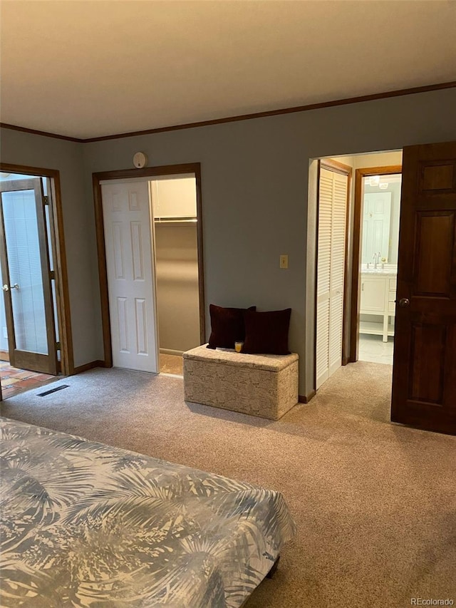 bedroom with multiple closets, crown molding, sink, and light colored carpet