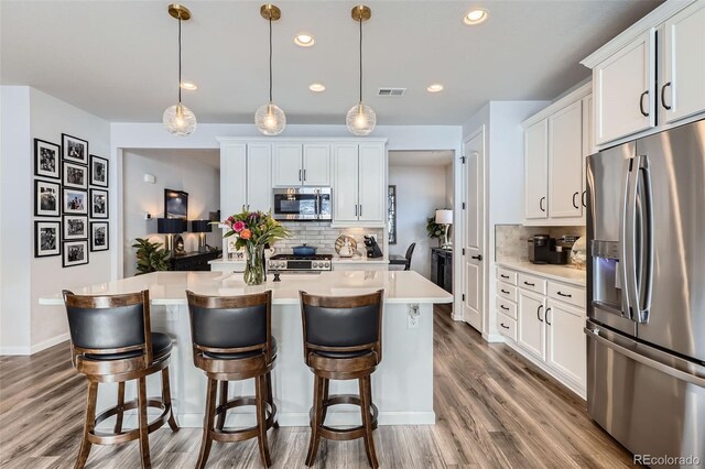 kitchen with visible vents, a center island with sink, light countertops, appliances with stainless steel finishes, and white cabinetry