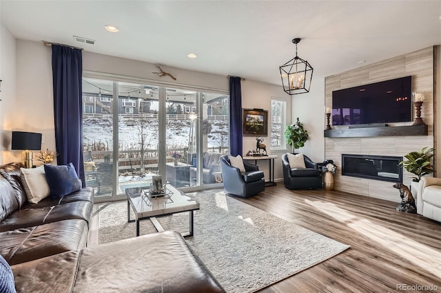 living room featuring visible vents, a tile fireplace, wood finished floors, a chandelier, and recessed lighting