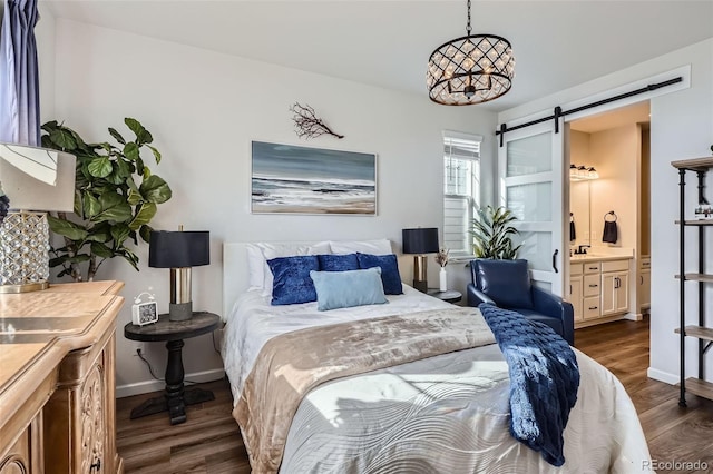 bedroom with dark wood-style flooring, baseboards, a barn door, and ensuite bath