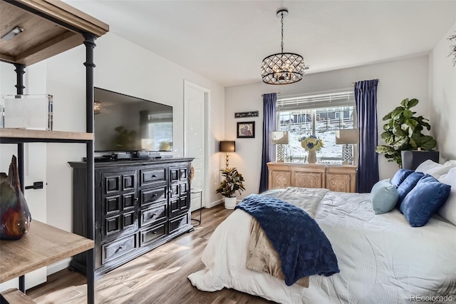 bedroom with baseboards, wood finished floors, and a chandelier