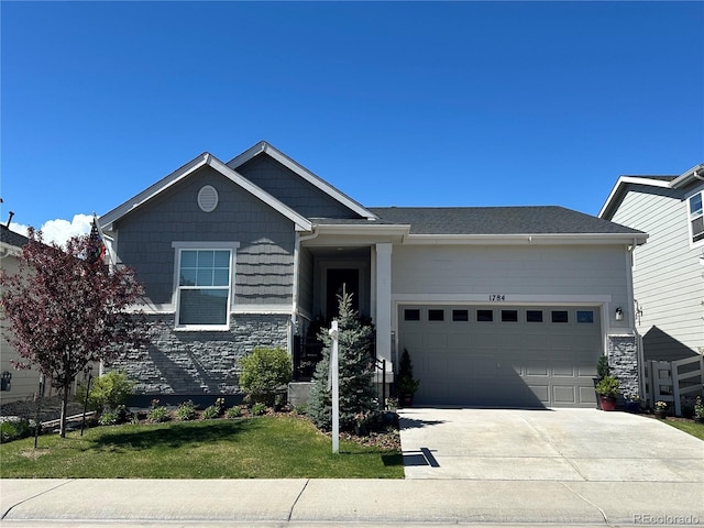 view of front facade featuring stone siding, driveway, a front yard, and a garage