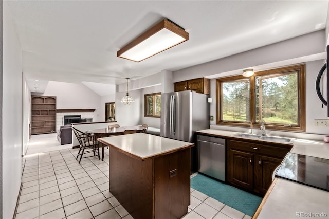 9420 Mcgill Ct, Parker, CO 80134 - kitchen with stainless steel appliances, a tiled fireplace, a center island, light tile patterned flooring, and vaulted ceiling