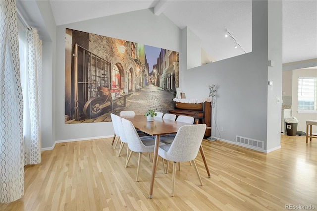 dining room with lofted ceiling with beams and light hardwood / wood-style floors