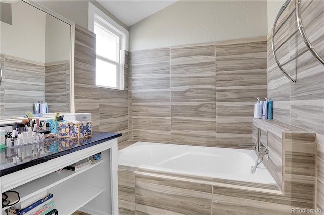 bathroom with vanity and tiled tub