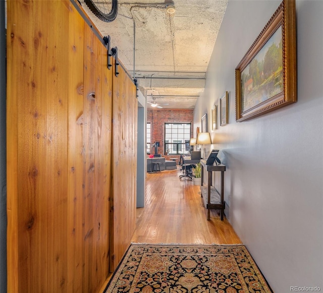 hall with a barn door and light hardwood / wood-style floors