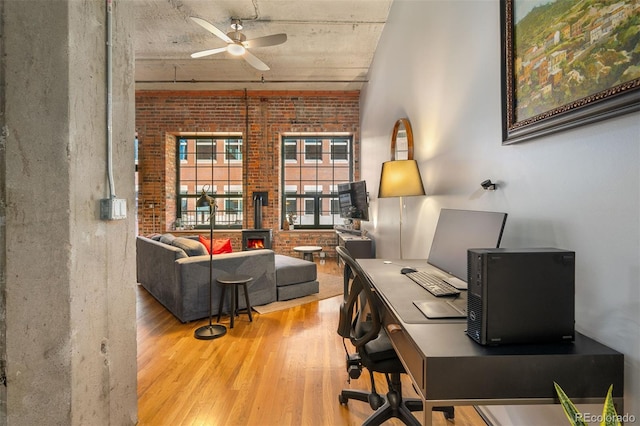 home office featuring ceiling fan, brick wall, and light hardwood / wood-style flooring