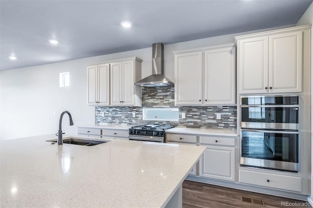 4947 N Quatar St, Aurora, CO 80019 - kitchen with wall chimney range hood, stainless steel appliances, decorative backsplash, light stone counters, and recessed lighting