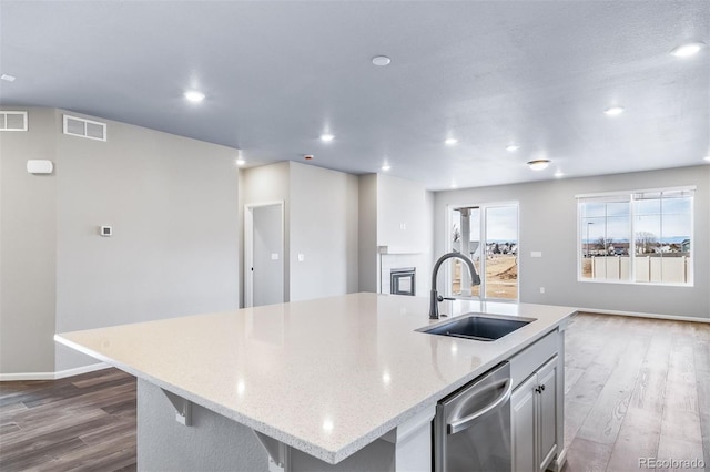 4947 N Quatar St, Aurora, CO 80019 - kitchen featuring stainless steel dishwasher, dark wood finished floors, recessed lighting, an island with sink, and light stone counters
