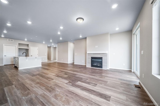 4947 N Quatar St, Aurora, CO 80019 - unfurnished living room featuring wood finished floors, a tiled fireplace, and recessed lighting