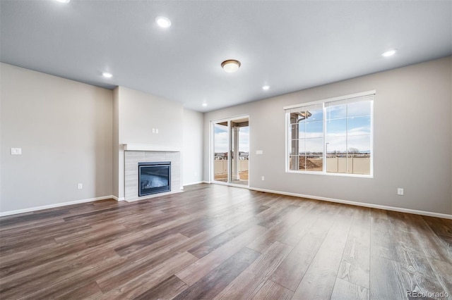 4947 N Quatar St, Aurora, CO 80019 - unfurnished living room with dark wood-style flooring, a tiled fireplace, and recessed lighting