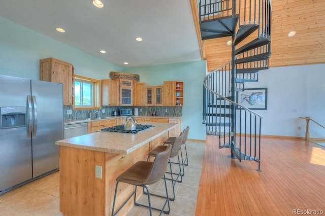 kitchen featuring a breakfast bar, backsplash, sink, a kitchen island, and stainless steel appliances