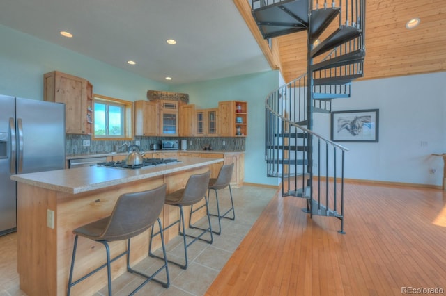 kitchen featuring a kitchen breakfast bar, decorative backsplash, a center island, and stainless steel appliances