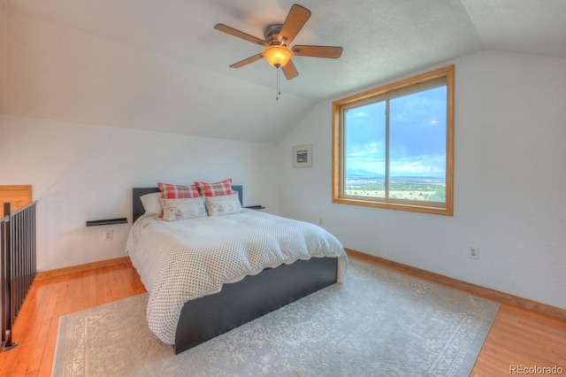 bedroom with hardwood / wood-style floors, vaulted ceiling, and ceiling fan