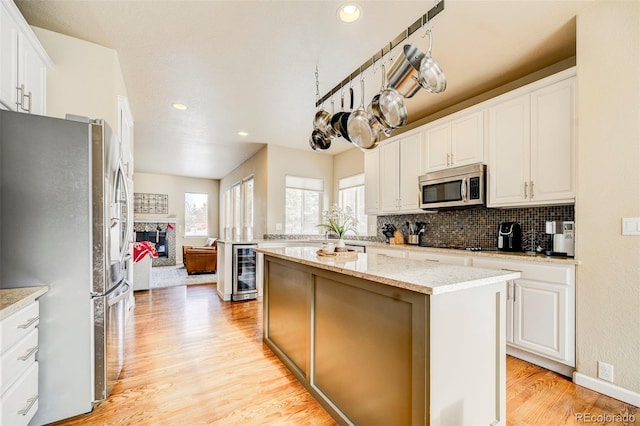 kitchen with white cabinetry, a kitchen island, beverage cooler, and appliances with stainless steel finishes