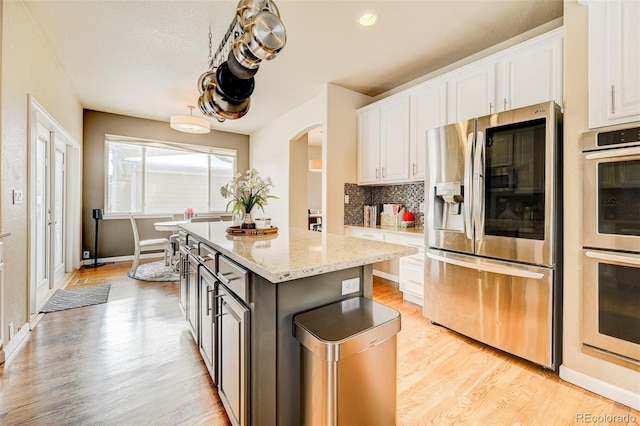 kitchen with white cabinets, appliances with stainless steel finishes, a center island, and light wood-type flooring