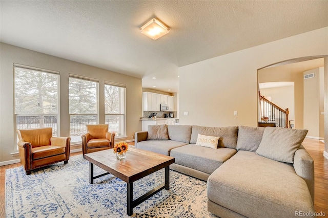 living room with a textured ceiling and light wood-type flooring