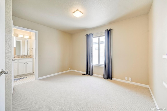 spare room with a textured ceiling, light colored carpet, and sink