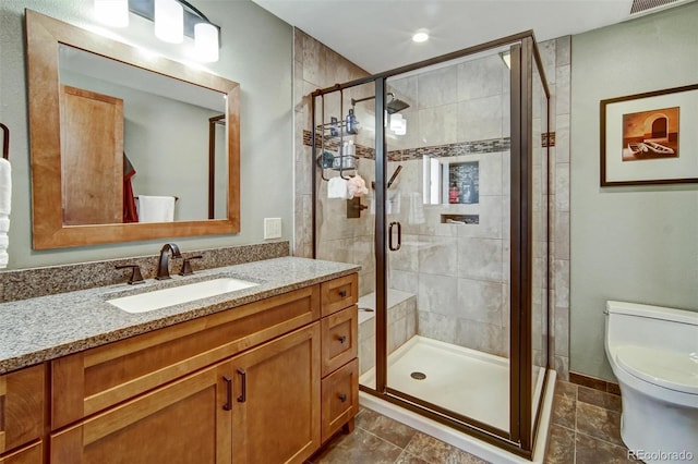 full bath with a shower stall, vanity, and toilet