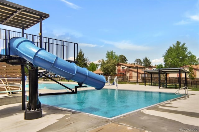 community pool featuring a water slide and fence