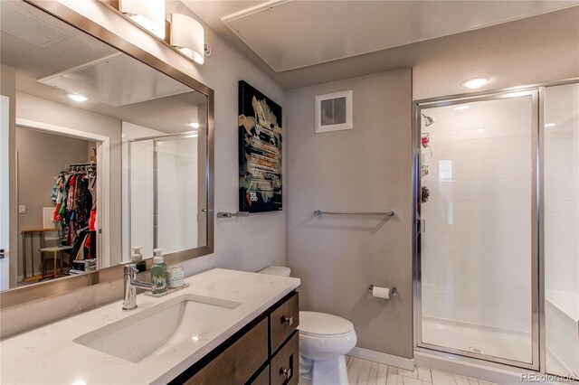 155 S Monaco Street Parkway Unit 311, Denver, CO 80224 - full bathroom featuring toilet, vanity, visible vents, a stall shower, and a walk in closet