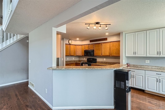 13155 W 63rd Pl, Arvada, CO 80004 - kitchen with black appliances, dark wood finished floors, a textured ceiling, brown cabinets, and light stone counters